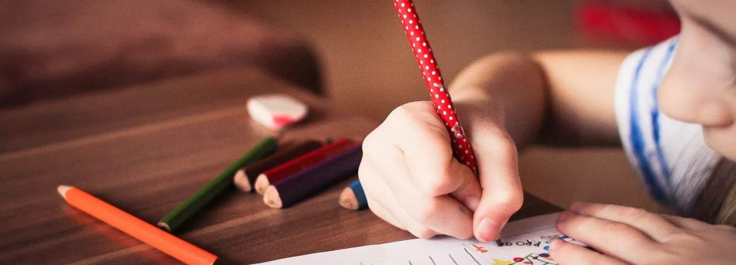 Photo d'une enfant en train d'écrire un devoir sur une table